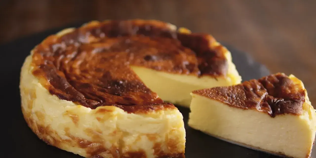 Tarta de queso al horno casera, dorada y cremosa, con una porción lista para disfrutar.