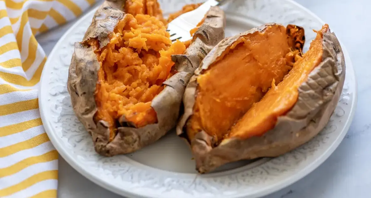 Boniato tierno y esponjoso hecho en air fryer, servido en plato blanco con un tenedor.