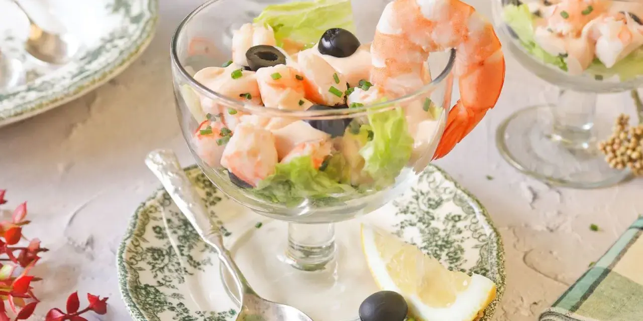 Delicioso cóctel de gambas servido en copa, con lechuga, aceitunas y un toque de limón. ¡Un clásico refrescante!