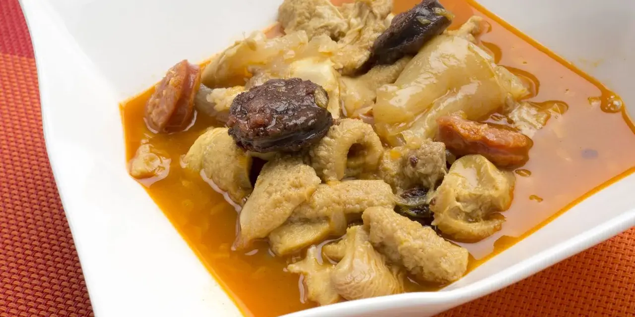 Un plato humeante de callos a la madrileña, con trozos de chorizo y morcilla en una rica salsa.