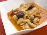 Un plato humeante de callos a la madrileña, con trozos de chorizo y morcilla en una rica salsa.