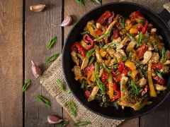 Sabroso wok de pollo con pimientos de colores y judías verdes, espolvoreado con semillas de sésamo y cebolleta.