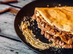 Crepe doblada con relleno cremoso de chocolate y trocitos de frutos secos. Ideal para aprender como hacer crepes deliciosos.