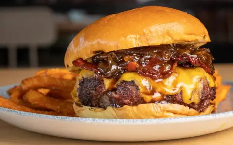 La mejor receta de hamburguesas caseras: jugosa carne, queso fundido, cebolla caramelizada y crujientes patatas fritas.