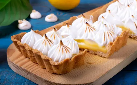 Tarta de limón con merengue suizo tostado, decorada con picos dorados.