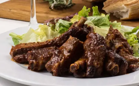 Costillas jugosas en freidora de aire, bañadas en salsa barbacoa y acompañadas de ensalada fresca. ¡Un manjar!