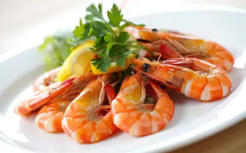 Plato de gambas al ajillo, jugosas y doradas, adornadas con perejil fresco y rodajas de limón.