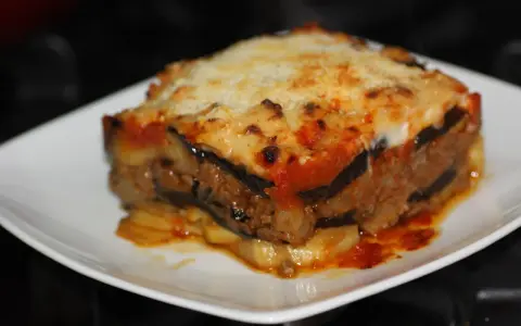 Porción de musaka casera con capas de berenjena, carne picada y salsa de tomate, gratinada con queso. ¡Una delicia de la musaka receta!