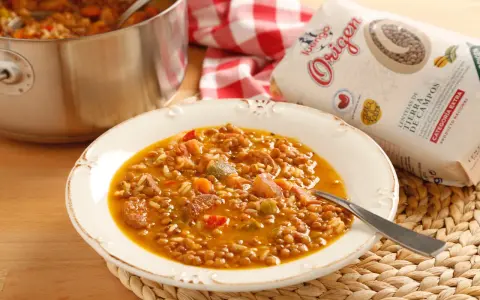 Plato de lentejas con arroz, chorizo y verduras. Una bolsa de lentejas "Origen" a un lado.