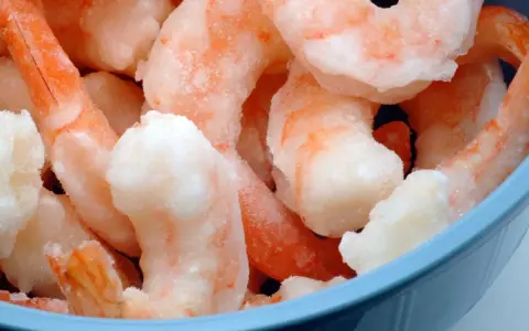 Langostinos cocidos congelados en un bol azul. Aprende cómo descongelar langostinos cocidos fácilmente para tus recetas.