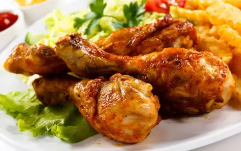 Crujientes muslos de pollo frito, acompañados de papas fritas, ensalada y tomate. ¡Un festín irresistible!