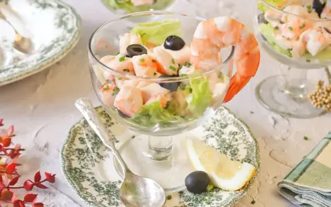 Delicioso cóctel de gambas servido en copa, con lechuga, aceitunas y un toque de limón. ¡Un clásico refrescante!