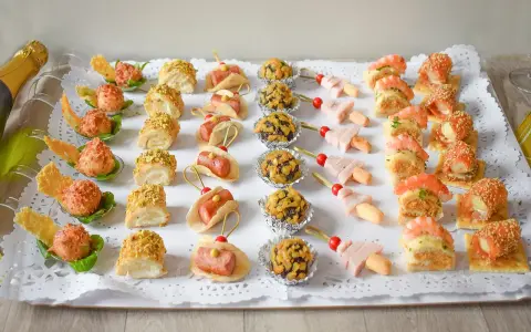 Bandeja con aperitivos navideños originales: mini tacos, bolitas de pistacho, brochetas de jamón y gambas, y rollitos de salmón.