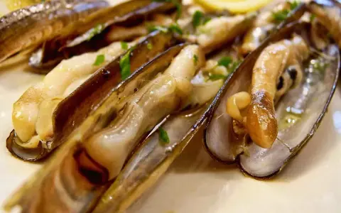 Navajas cocinadas en su jugo, con perejil picado y una rodaja de limón. ¡Estas navajas se pueden congelar para disfrutarlas más tarde!