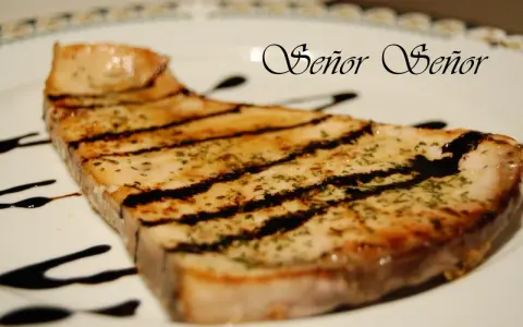 Un delicioso emperador a la plancha, con marcas de parrilla y un toque de hierbas, bañado en salsa oscura. ¡Un manjar digno de un Señor!