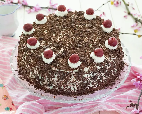 Deliciosa tarta Selva Negra, cubierta de virutas de chocolate y coronada con cerezas y nata.