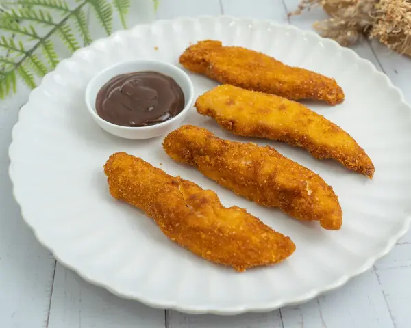 Cuatro crujientes fingers de pollo dorados, servidos en un plato blanco con una pequeña taza de salsa barbacoa.