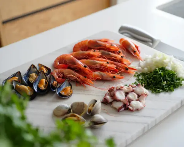 Ingredientes listos para un delicioso salpicón de marisco: gambas, mejillones, pulpo, almejas, cebolla y perejil picados.