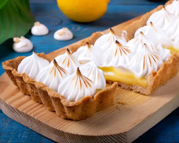 Tarta de limón con merengue suizo tostado, decorada con picos dorados.