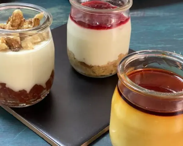 Tres postres en frascos: uno con nueces, otro con mermelada y galleta, y un flan de queso con caramelo.