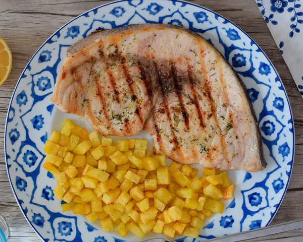 Pez espada filete a la parrilla con patatas fritas crujientes y limón. Un plato delicioso y saludable.