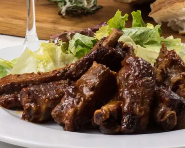 Costillas jugosas en freidora de aire, bañadas en salsa barbacoa y acompañadas de ensalada fresca. ¡Un manjar!