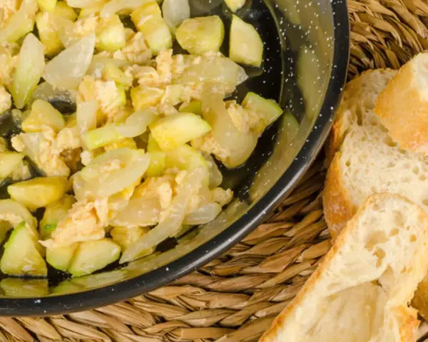 Zarangollo murciano, un revuelto de calabacín y cebolla, servido en sartén con pan rústico.