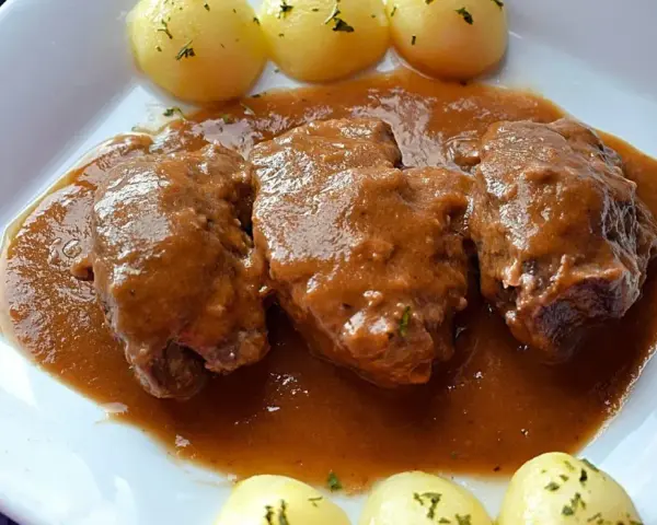Carrilleras al vino tinto, tiernas y jugosas, bañadas en una rica salsa, acompañadas de patatas cocidas.