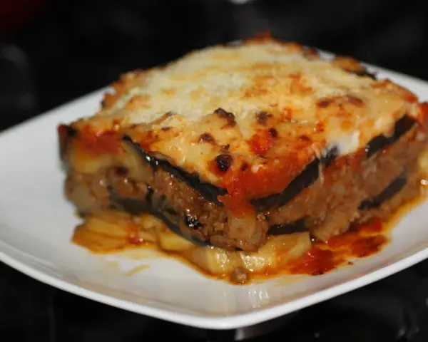 Porción de musaka casera con capas de berenjena, carne picada y salsa de tomate, gratinada con queso. ¡Una delicia de la musaka receta!