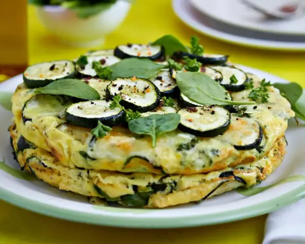 Deliciosa tortilla de calabacín y espinacas, coronada con rodajas de calabacín y hierbas frescas.