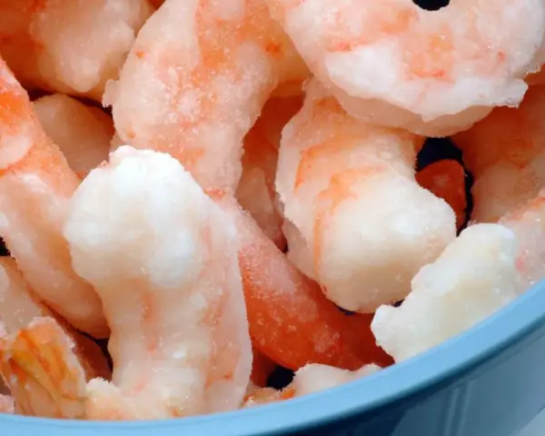 Langostinos cocidos congelados en un bol azul. Aprende cómo descongelar langostinos cocidos fácilmente para tus recetas.