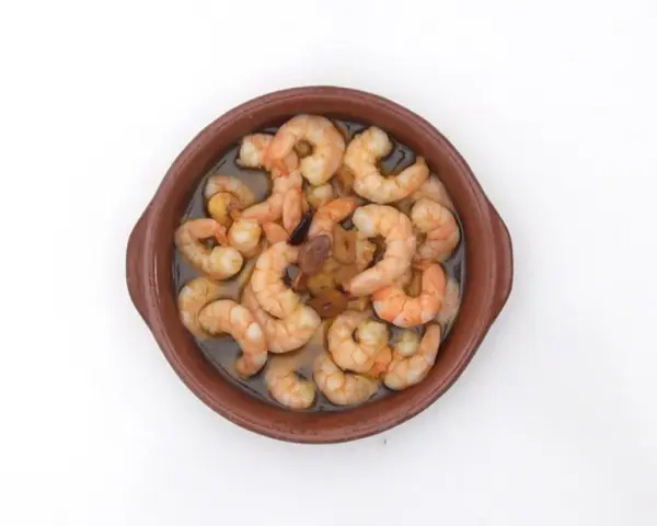 Gambas al pil pil burbujeantes en cazuela de barro, con ajo y aceite de oliva.