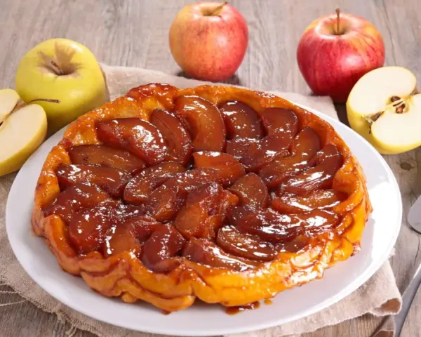Deliciosa tarta tatin dorada y caramelizada, rodeada de manzanas frescas. Perfecta para compartir.