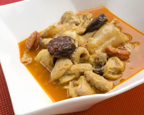 Un plato humeante de callos a la madrileña, con trozos de chorizo y morcilla en una rica salsa.