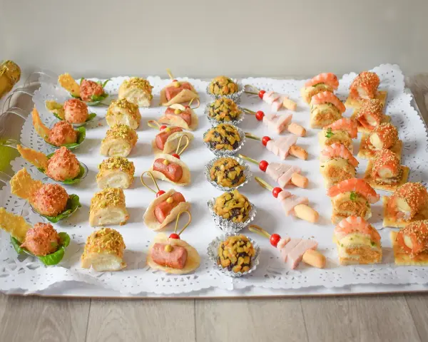 Bandeja con aperitivos navideños originales: mini tacos, bolitas de pistacho, brochetas de jamón y gambas, y rollitos de salmón.