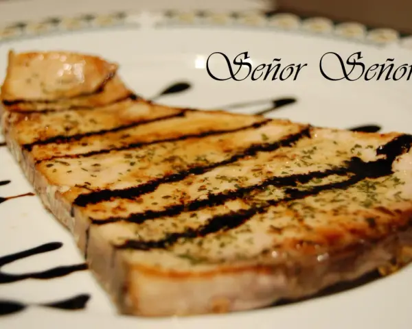 Un delicioso emperador a la plancha, con marcas de parrilla y un toque de hierbas, bañado en salsa oscura. ¡Un manjar digno de un Señor!