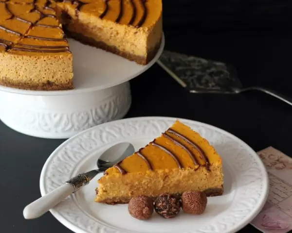 Deliciosa tarta de queso de calabaza con un toque de chocolate, servida en un plato blanco con tres trufas.