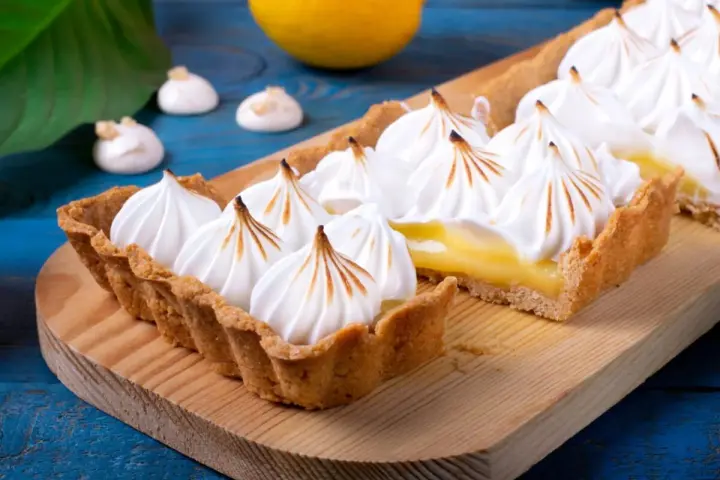 Tarta de limón con merengue suizo tostado, decorada con picos dorados.
