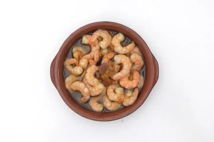 Gambas al pil pil burbujeantes en cazuela de barro, con ajo y aceite de oliva.