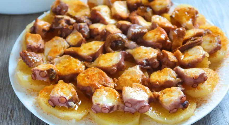 Pulpo a la gallega servido sobre patatas cocidas, con pimentón espolvoreado. ¡Un plato delicioso!