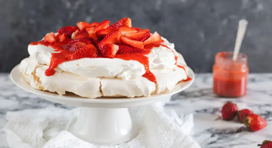 Deliciosa tarta pavlova con fresas frescas y salsa de fresa, lista para ser disfrutada.