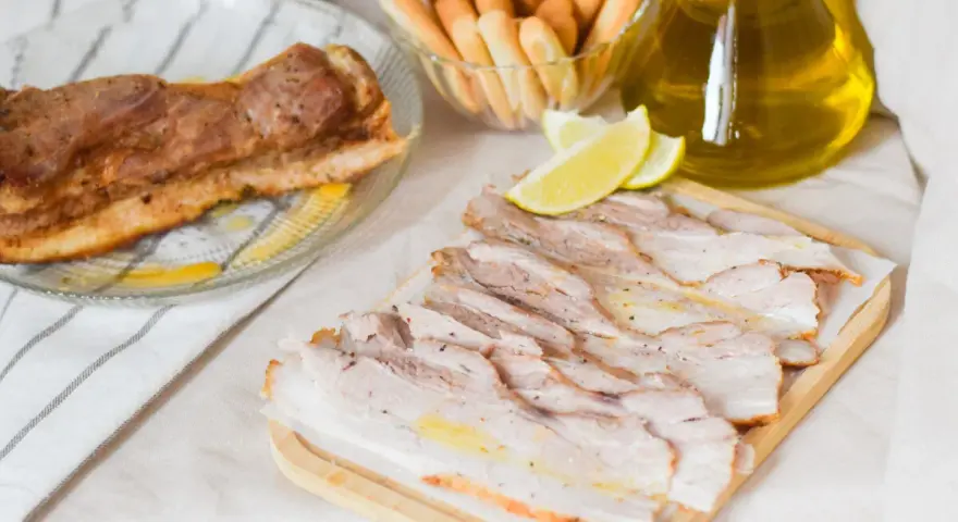 Chicharrón de Cádiz, lonchas de panceta crujiente, palitos de pan y aceite de oliva.