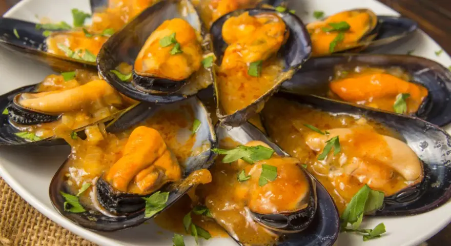 Mejillones en salsa, humeantes y listos para disfrutar. Un plato delicioso con un toque de perejil fresco.