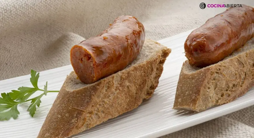 Chorizo a la sidra jugoso sobre pan rústico, decorado con perejil fresco. Un bocado delicioso.