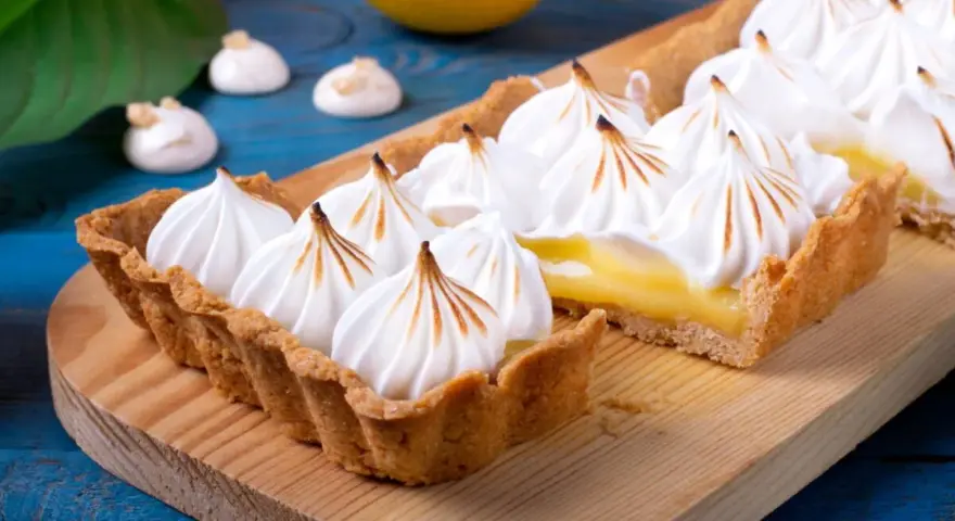 Tarta de limón con merengue suizo tostado, decorada con picos dorados.