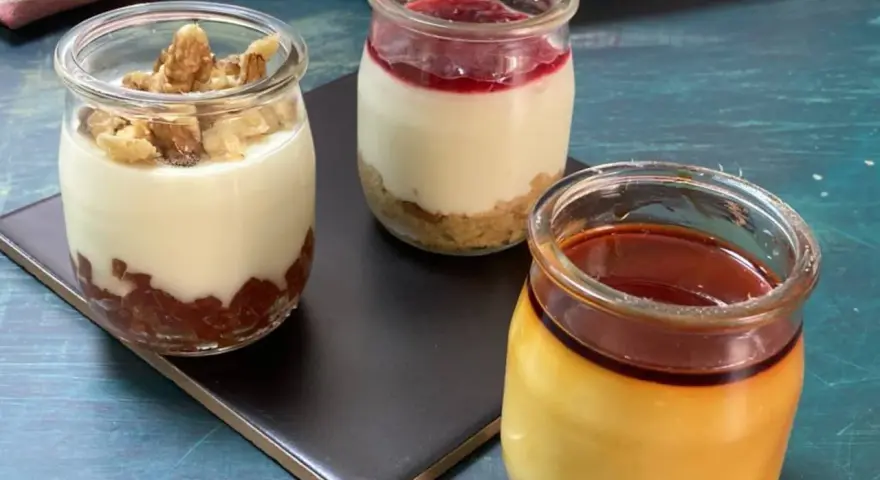 Tres postres en frascos: uno con nueces, otro con mermelada y galleta, y un flan de queso con caramelo.
