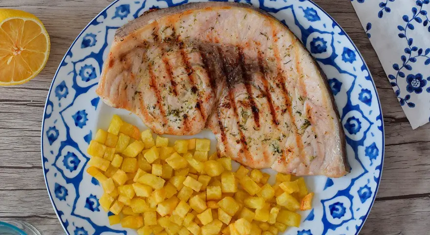 Pez espada filete a la parrilla con patatas fritas crujientes y limón. Un plato delicioso y saludable.
