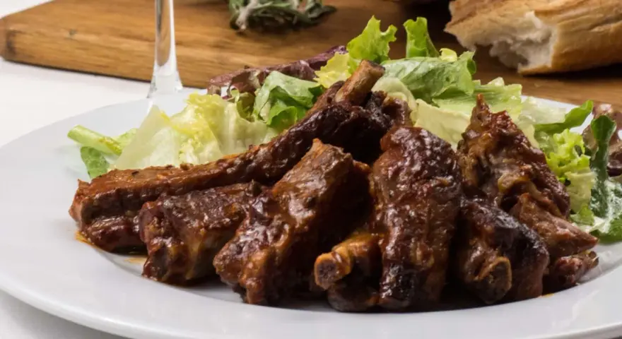 Costillas jugosas en freidora de aire, bañadas en salsa barbacoa y acompañadas de ensalada fresca. ¡Un manjar!