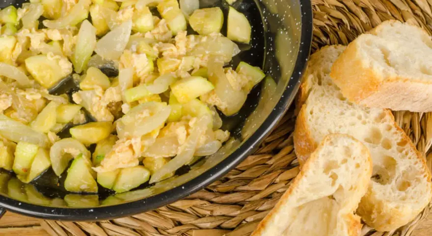 Zarangollo murciano, un revuelto de calabacín y cebolla, servido en sartén con pan rústico.