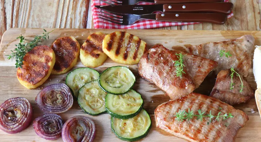Delicioso escalope de ternera a la parrilla con patatas, calabacín y cebolla morada.